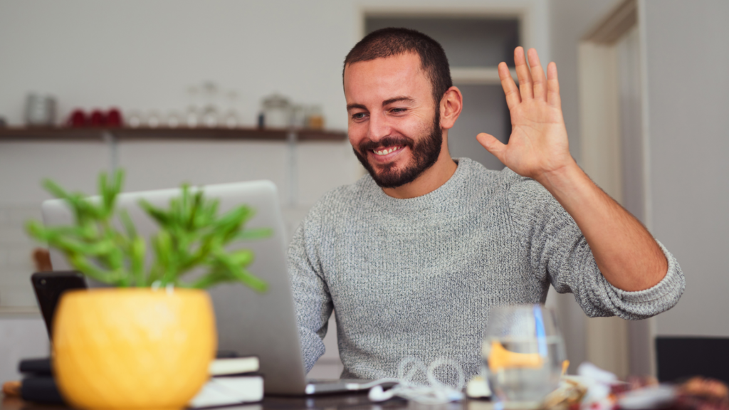 A man waving at his laptop, showcasing his satisfaction with the personalised banking experience made possible by Composite AI.