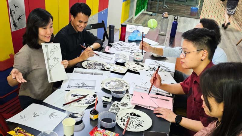 Instructor showing an ink painting to 4 students.